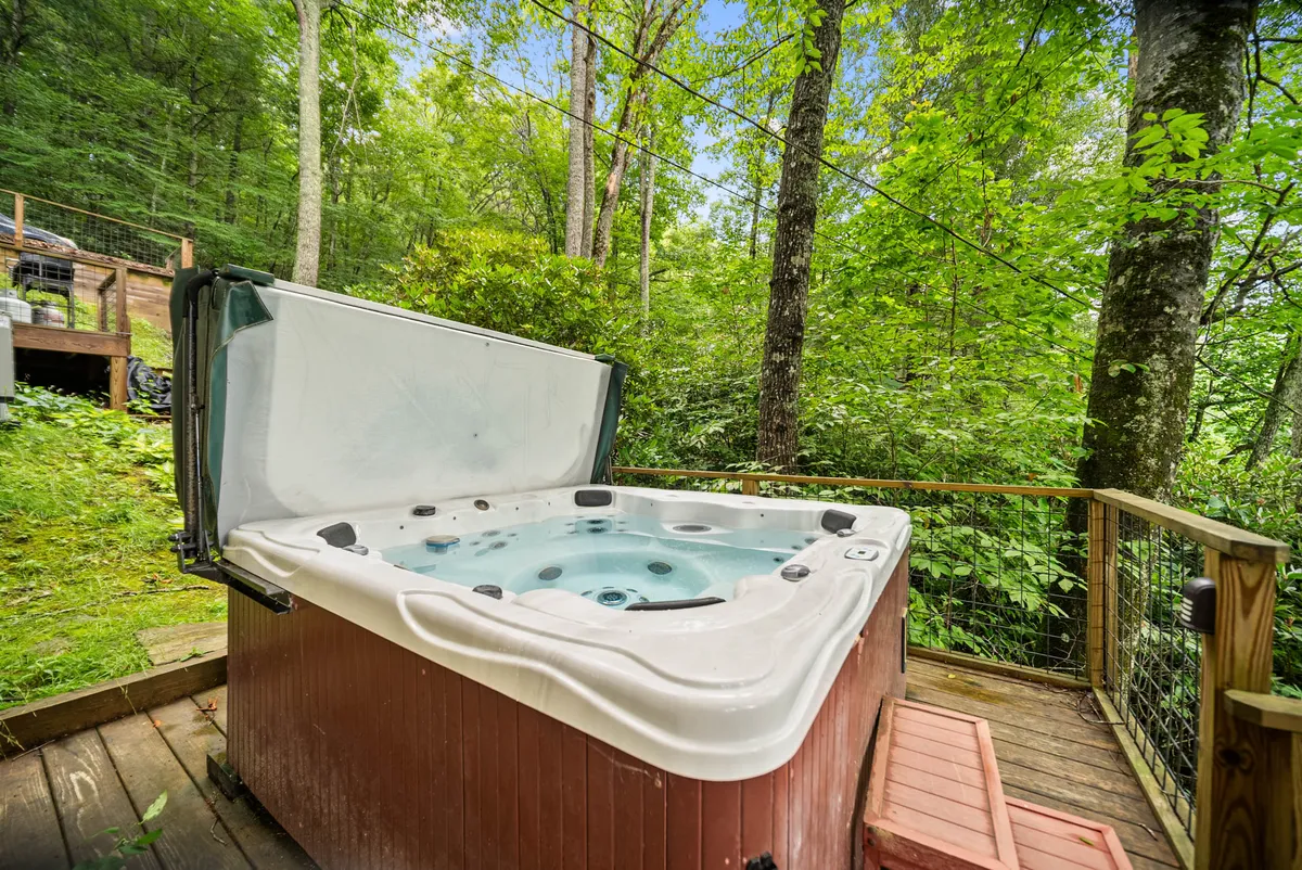 This image showcases a private hot tub situated on a wooden deck surrounded by lush greenery. The setting is serene and inviting, suggesting a perfect place to relax and unwind while enjoying nature. The perspective allows viewers to imagine soaking in the tub, perhaps with a view of the sunset or the stars above.